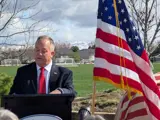 Mayor Simison speaking at Heroes Park with Flag behind him